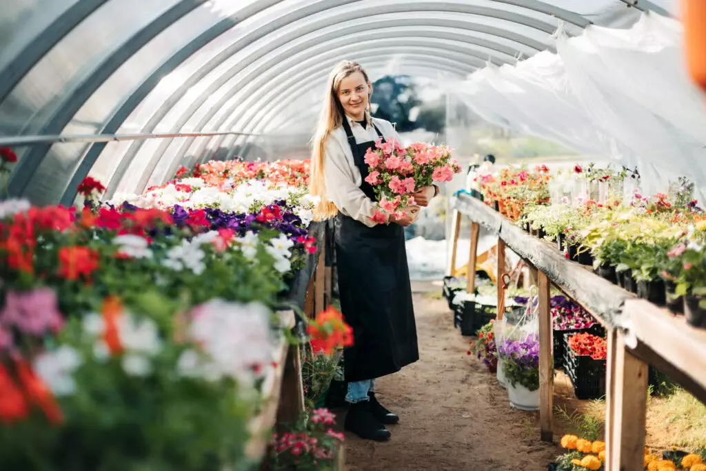 Frau im Gewächshaus mit Blumensträußen